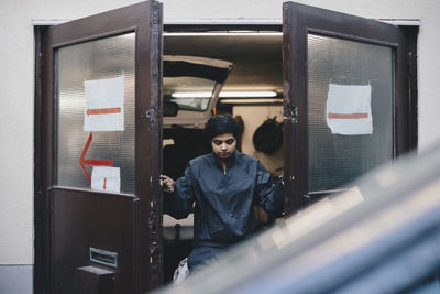 Female auto mechanic opening doors of repair shop