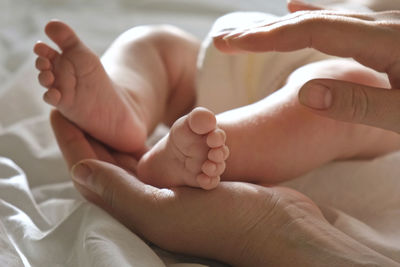 Cropped image of baby on bed