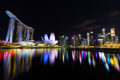 Illuminated city by river at night