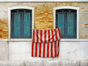 Fabric hanging by old windows against wall outdoors