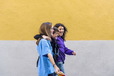 Young diverse friends walking on the street with pride rainbow flag.