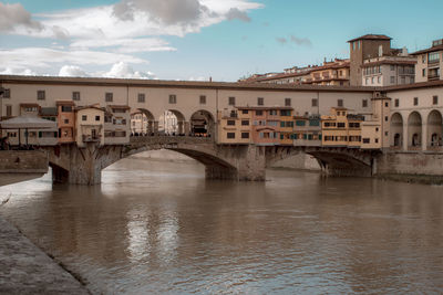 Arch bridge over river against buildings in city