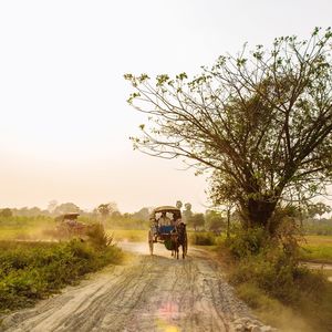 People riding bicycle on road against sky