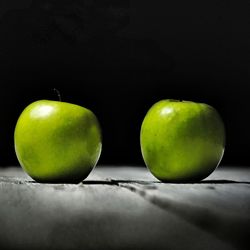Close-up of green apples on table against black background
