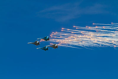 Low angle view of airshow against clear blue sky