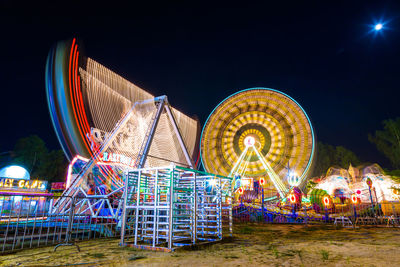 Illuminated ferris wheel against sky at night