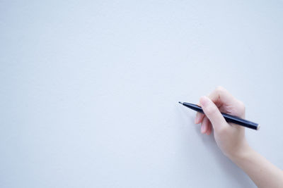 Close-up of hand holding paper against white background