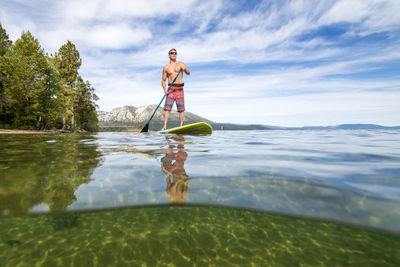 A man stand up paddle boarding on lake tahoe, ca