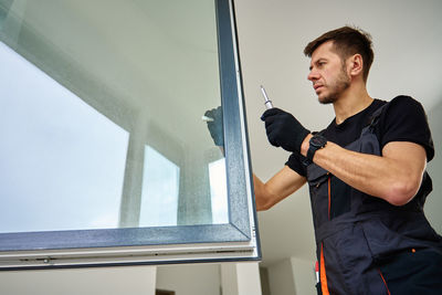 Portrait of young man looking through window