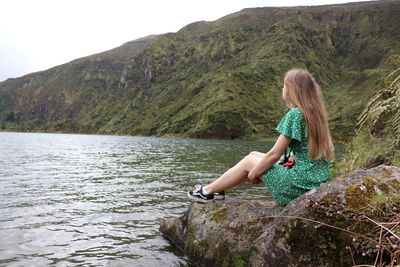 Woman looking at waterfall against mountain range