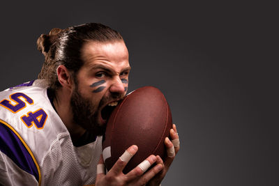 Portrait of young man holding ball against black background