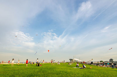 Group of people playing soccer on field against sky