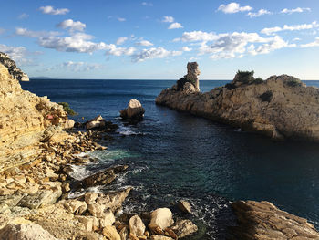 Rocks on sea shore against sky
