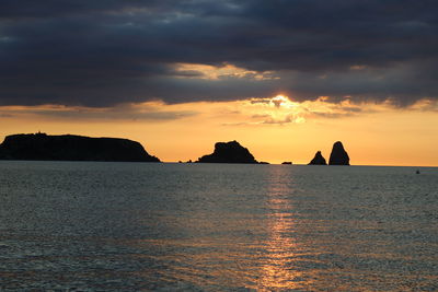 Scenic view of sea against dramatic sky during sunset