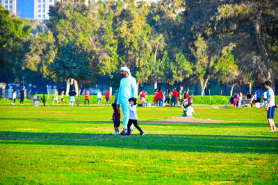 People standing on field against trees