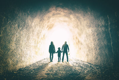 Rear view of people walking in tunnel