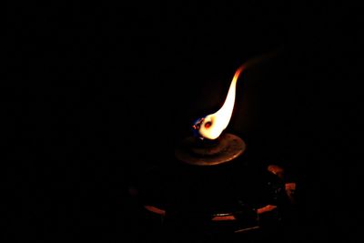 Close-up of lit candle against black background