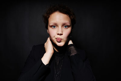 Portrait of young woman against black background