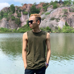 Young man wearing sunglasses standing by lake
