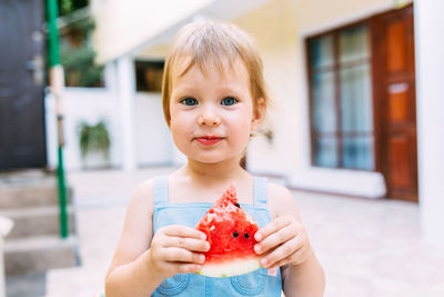 Little cute cheerful girl eating a slice of watermelon close up.