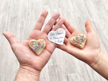Cropped hands holding heart shape biscuits and message over pathway