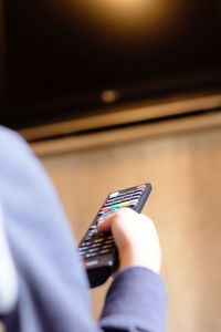 Close-up of boy changing channels on tv while relaxing at home.