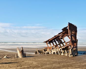 Wooden structure on beach against sky