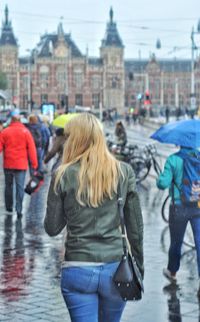 Rear view of women walking on wet city street