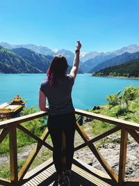 Rear view of woman standing on railing against mountain