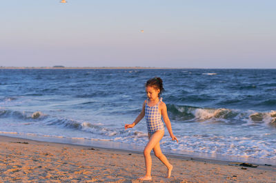 Young girl running on the beach at sunset