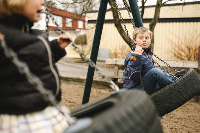 Sister swinging with brother having disability in park