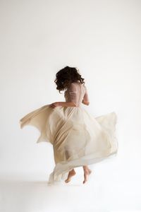 Rear view of woman dancing against white background