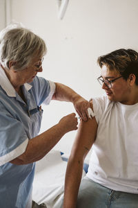 Senior female doctor injecting male patient at medical clinic