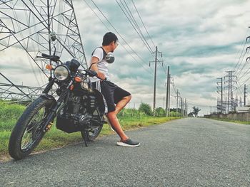 Man riding bicycle on road against sky