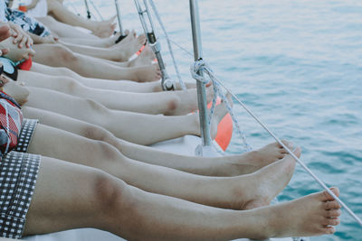 Low section of women sitting on sailboat in sea