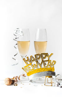 Glasses of champagne and happy new year hat on white background.