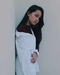 Young woman standing against wall