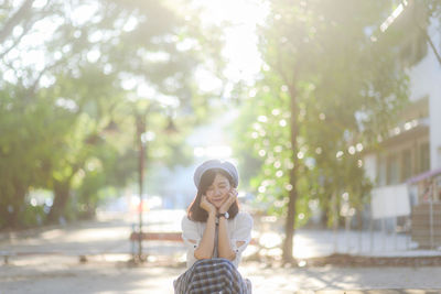 Smiling young woman with eyes closed sitting at park