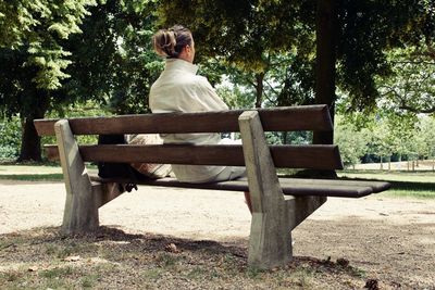 Rear view of woman sitting on bench in park