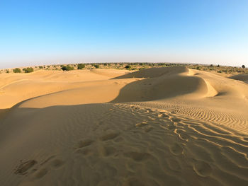 Sand dunes in desert against clear blue sky