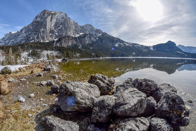 Rocks by lake against mountain range against sky