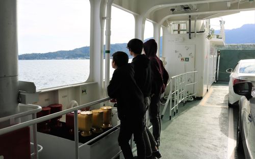 Rear view of people standing on boat at sea