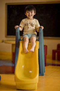 Portrait of smiling boy sitting on slide