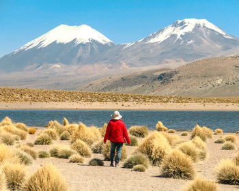 Rear view of woman standing on field against snowcapped mountains