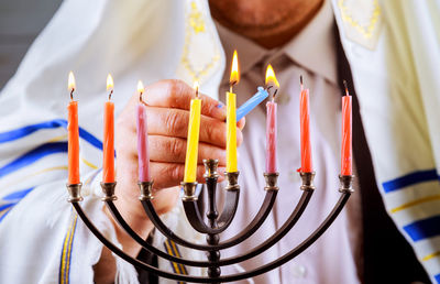 Midsection of man burning colorful candles