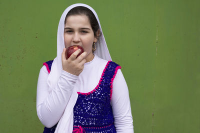 Portrait of beautiful young woman standing against wall