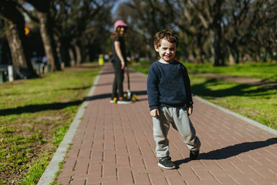 Portrait of young woman walking on footpath
