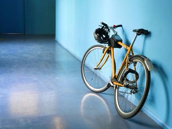 Yellow bicycle parked against blue wall in building