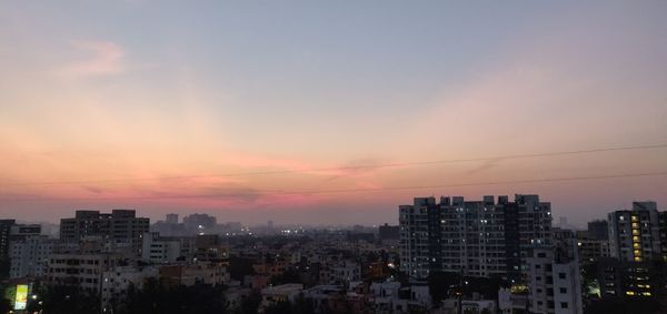 Buildings in city against sky at sunset