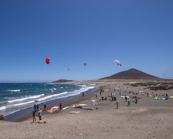 Group of people on beach against blue sky